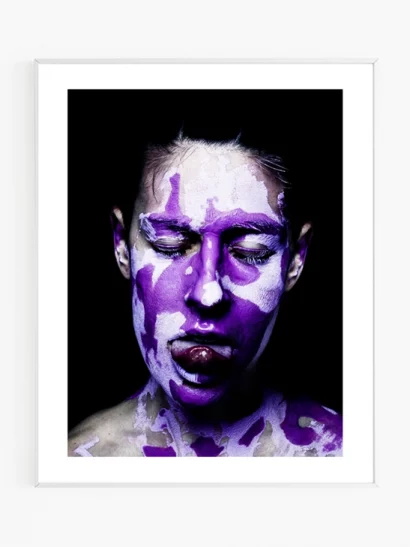 Photographie artistique intitulée "Purple", représentant un portrait de face d'une personne qui a les yeux fermés, qui tire la langue et qui est recouverte d'argile violette.